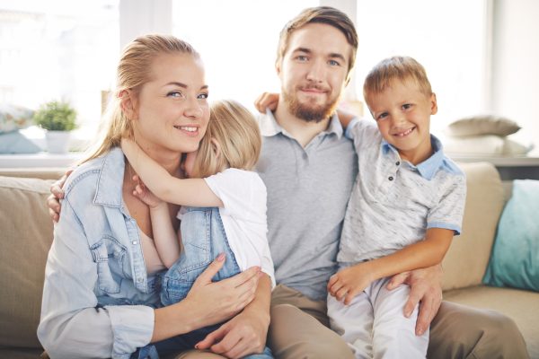 Happy Family On Couch In Comfortable Home After HVAC Maintenance