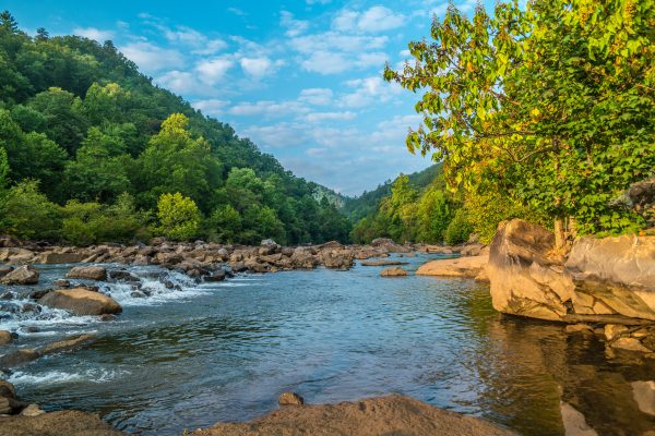 Early morning sunrise shining on the rocks and boulders at the Ocoee river with the water just released from the dam #2 flowing rapidly downstream on a bright sunny day in autumn