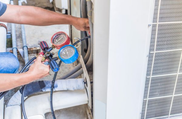 HVAC maintenance mechanic using measuring equipment