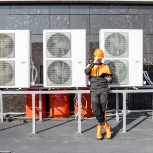 HVAC Service Expert Egineer standing near the outdoor units of the air conditioner