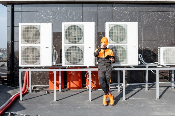 HVAC Service Expert Egineer standing near the outdoor units of the air conditioner