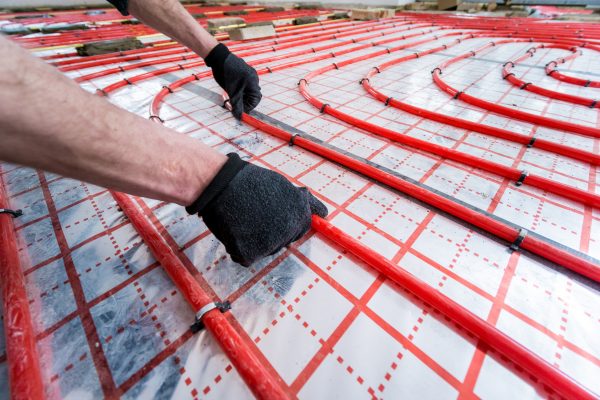 Workers Hands Installing Tubing For A Hydronic Radiant Floor Heating System