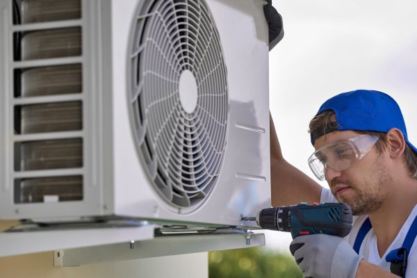 HVAC technician performing air conditioner condenser maintenance service for residential cooling system in Metro Atlanta