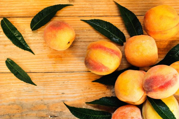 Fresh peaches on a wooden surface representing spring in Atlanta, connecting seasonal changes to the importance of preparing your Buckhead home with HVAC maintenance before warmer temperatures arrive.