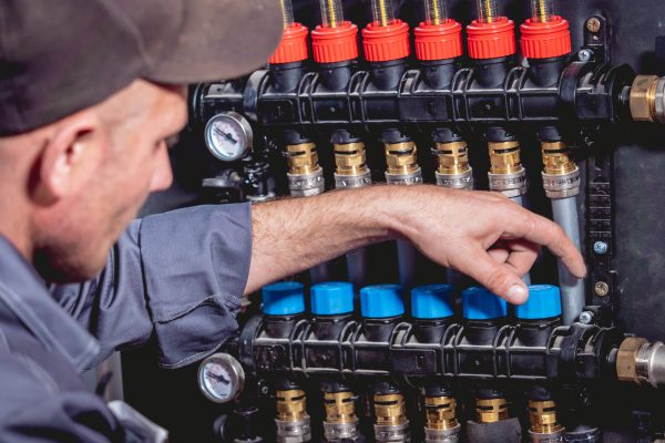 HVAC technician adjusting geothermal loop flow controls and manifold valves during WaterFurnace system diagnostics, WaterFurnace freeze detection faults, low water flow issues, geothermal heat pump troubleshooting, and professional geothermal HVAC service.