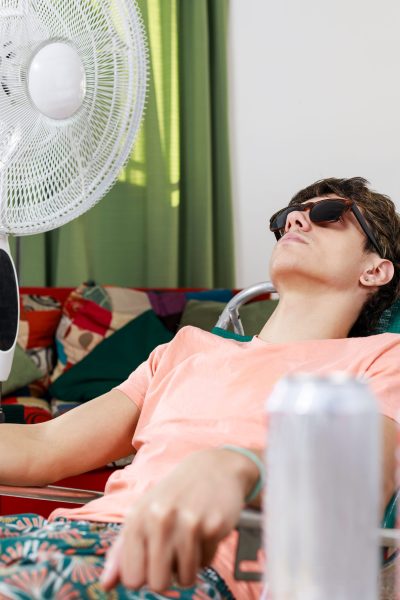 Homeowner using a fan indoors while dealing with heat pump cooling issues during hot Atlanta weather